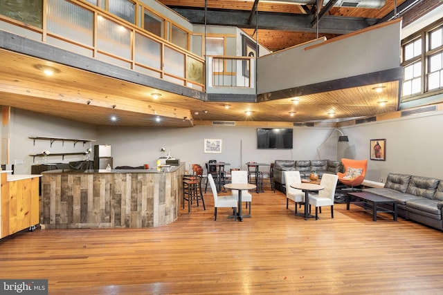 kitchen featuring light hardwood / wood-style floors, a kitchen bar, decorative light fixtures, and a towering ceiling