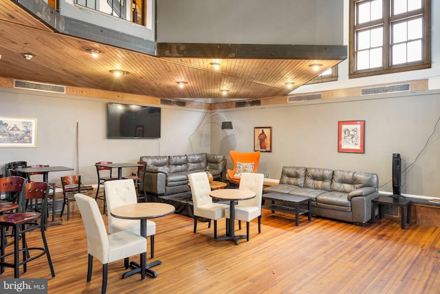 living room featuring a high ceiling, wooden ceiling, and light hardwood / wood-style flooring