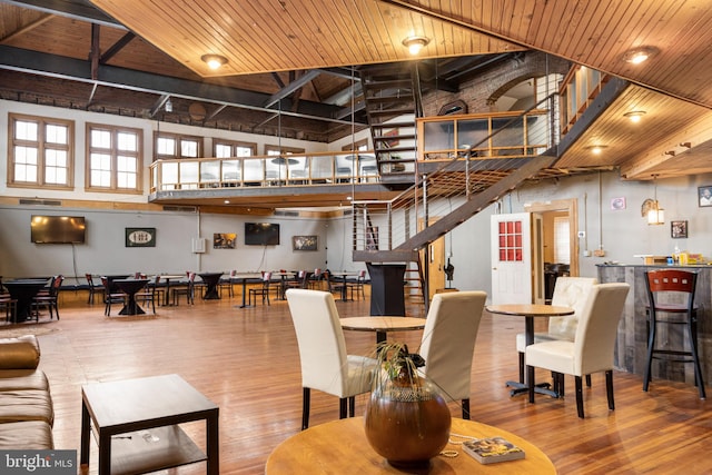 dining space with a towering ceiling, light wood-type flooring, and wood ceiling