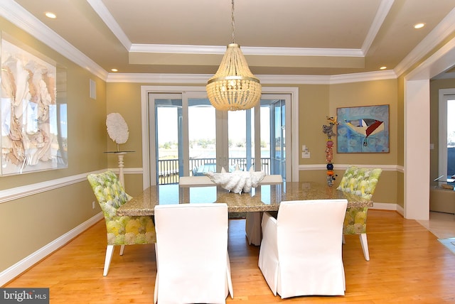 dining room featuring a raised ceiling, light hardwood / wood-style floors, and an inviting chandelier