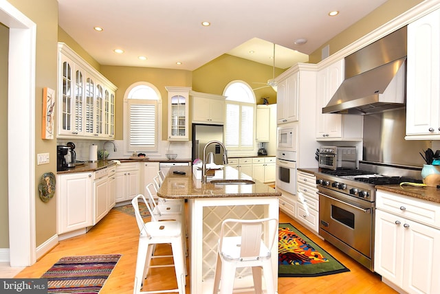 kitchen featuring sink, appliances with stainless steel finishes, light hardwood / wood-style floors, a center island with sink, and tasteful backsplash