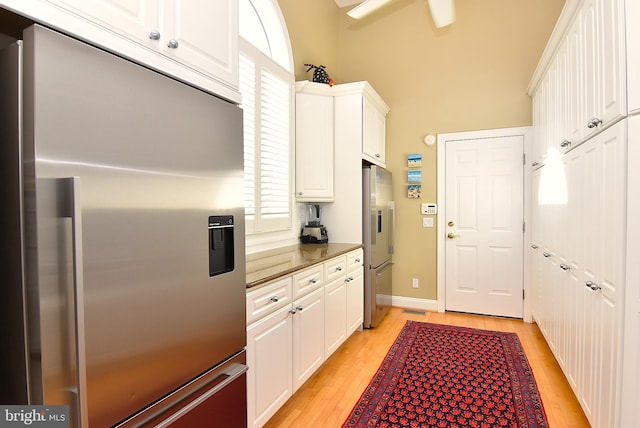 kitchen with high end refrigerator, light hardwood / wood-style floors, and white cabinets