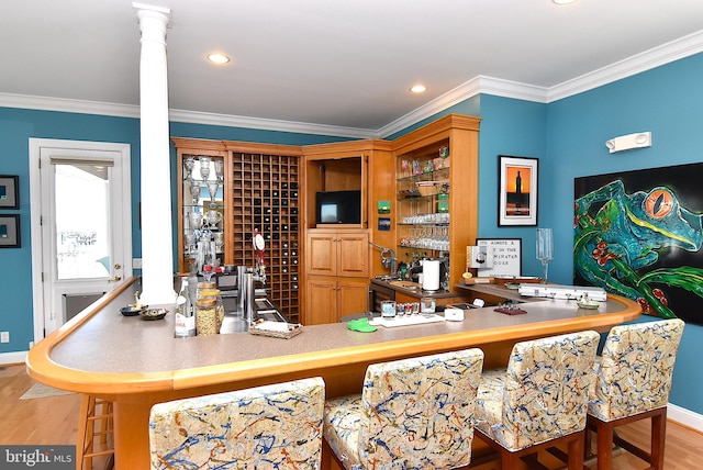 bar featuring light hardwood / wood-style floors, decorative columns, and crown molding