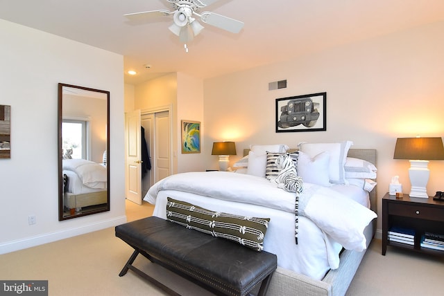 bedroom with ceiling fan, light carpet, and a closet