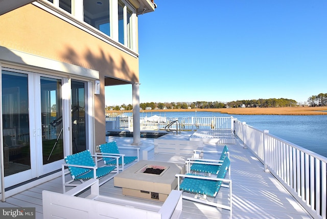 deck with a water view and a fire pit