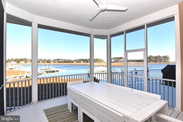 sunroom with ceiling fan and a water view