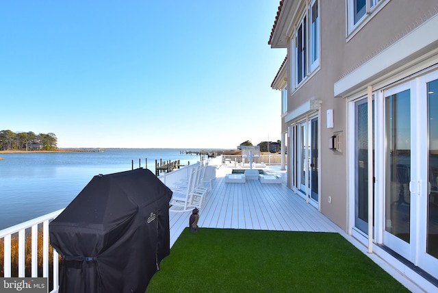 wooden terrace featuring french doors, a water view, and a yard