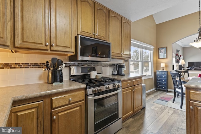 kitchen featuring pendant lighting, stainless steel appliances, backsplash, dark hardwood / wood-style flooring, and ornamental molding