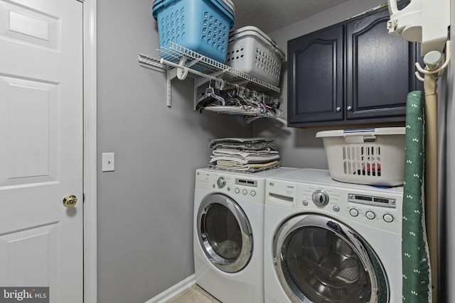 washroom featuring cabinets, a textured ceiling, and washing machine and clothes dryer