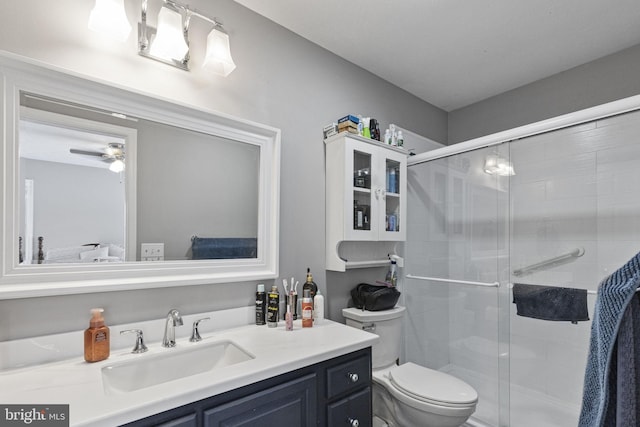 bathroom with vanity, a shower with door, ceiling fan, and toilet