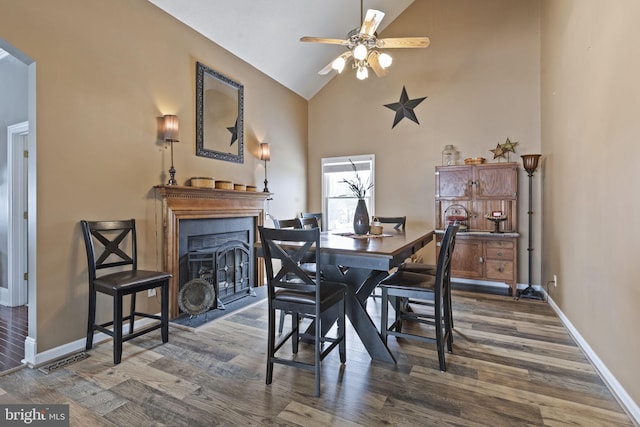 dining area with high vaulted ceiling, ceiling fan, and dark wood-type flooring