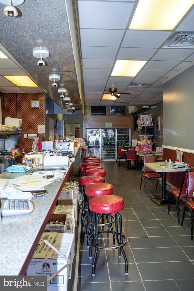 tiled dining area featuring a drop ceiling