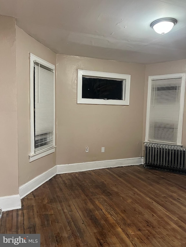 unfurnished room featuring radiator and dark hardwood / wood-style flooring