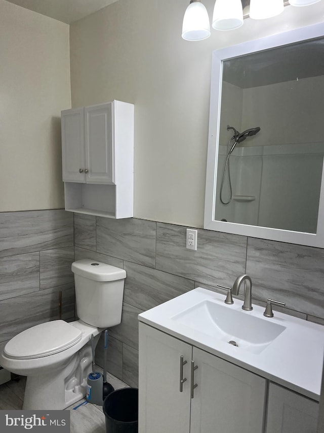 bathroom featuring vanity with extensive cabinet space, backsplash, toilet, and tile walls