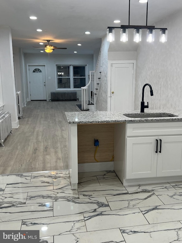 kitchen featuring white cabinetry, ceiling fan, light hardwood / wood-style flooring, sink, and radiator heating unit