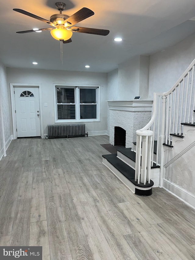 living room with ceiling fan, light wood-type flooring, and radiator