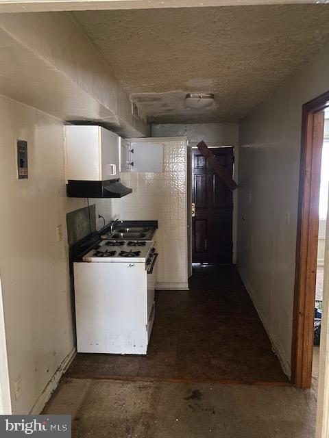 kitchen with white gas stove, a sink, and white cabinets