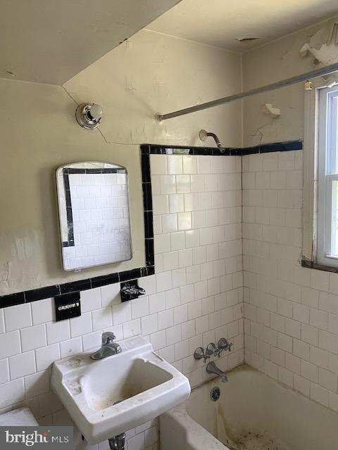 bathroom featuring a sink, tile walls, and bathtub / shower combination