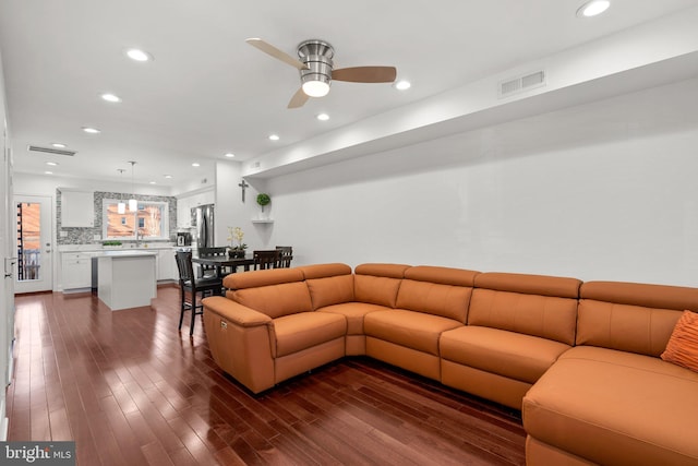 living room with dark hardwood / wood-style flooring and ceiling fan