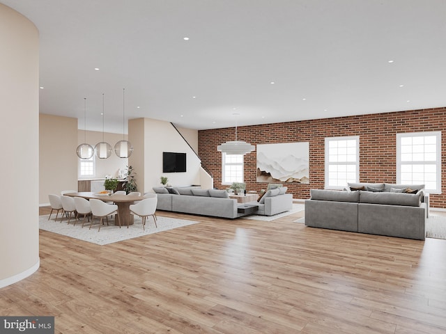 living room featuring brick wall, light hardwood / wood-style floors, and a healthy amount of sunlight