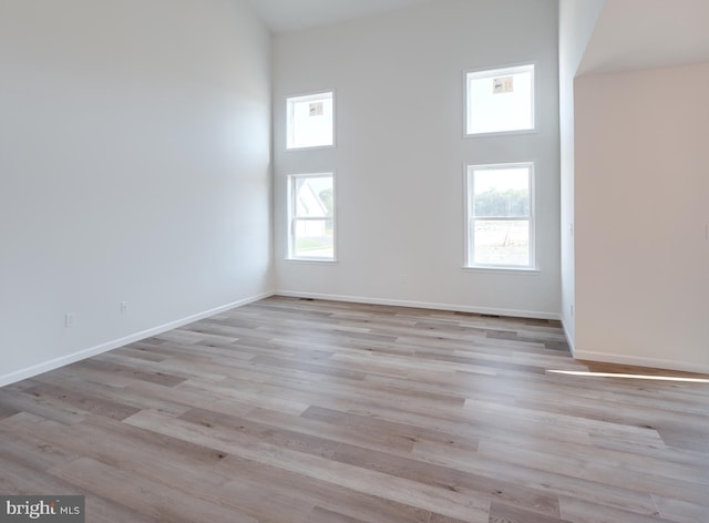 spare room with a towering ceiling and light hardwood / wood-style floors