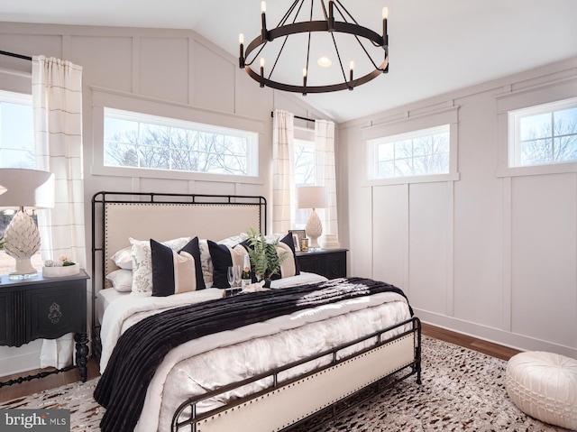 bedroom with lofted ceiling, hardwood / wood-style floors, and a notable chandelier