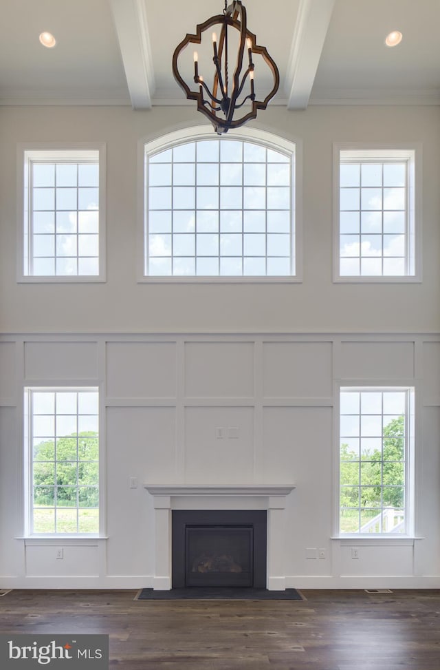 unfurnished living room featuring crown molding, dark hardwood / wood-style flooring, beam ceiling, and a chandelier