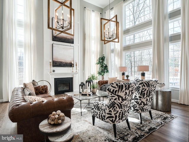 living room with dark wood-type flooring, a chandelier, and a towering ceiling