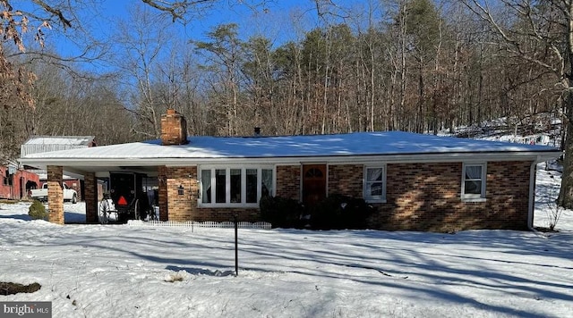 snow covered back of property featuring a carport