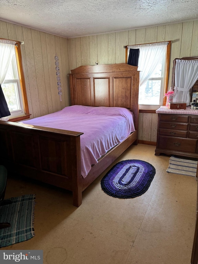 bedroom featuring wood walls and a textured ceiling