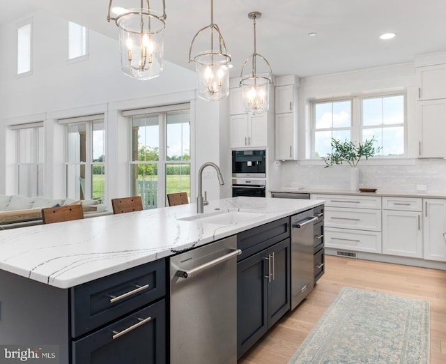 kitchen with backsplash, a center island with sink, appliances with stainless steel finishes, and plenty of natural light