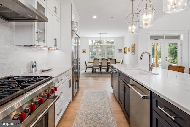 kitchen featuring white cabinets, backsplash, pendant lighting, and wall chimney range hood