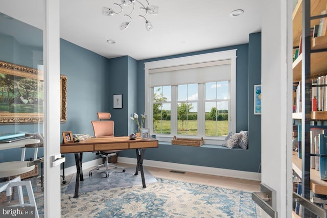 home office featuring an inviting chandelier and light hardwood / wood-style flooring