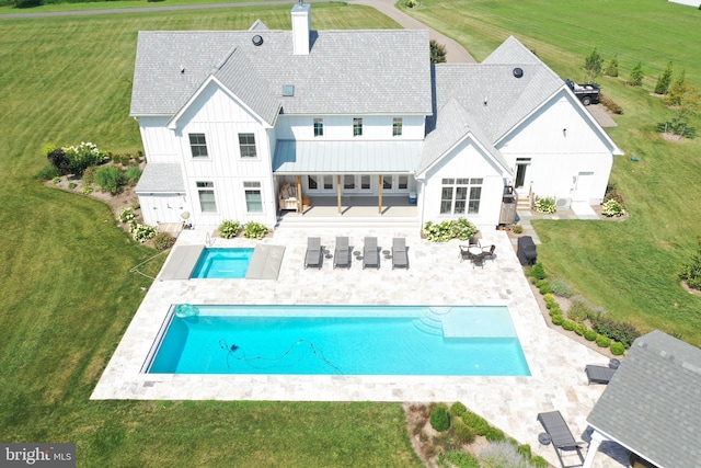 rear view of house featuring a rural view, a patio area, and a yard