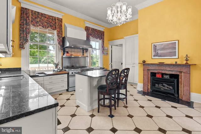 kitchen with high end stainless steel range, white cabinetry, a notable chandelier, wall chimney range hood, and a kitchen breakfast bar