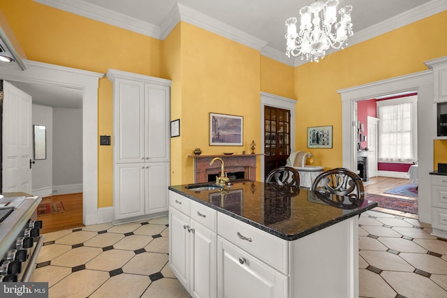 kitchen with an inviting chandelier, hanging light fixtures, ornamental molding, and a center island with sink