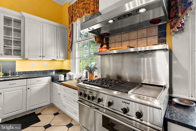 kitchen featuring white cabinetry, light tile floors, range with two ovens, sink, and extractor fan