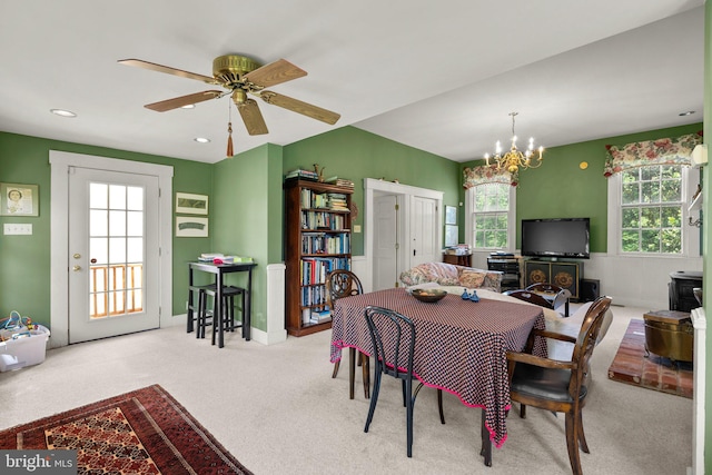 carpeted dining space featuring ceiling fan with notable chandelier and a healthy amount of sunlight