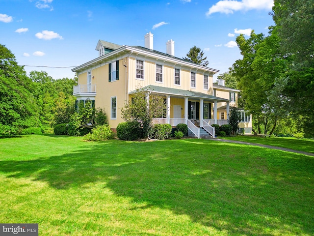 view of front of property featuring a front lawn, a balcony, and covered porch