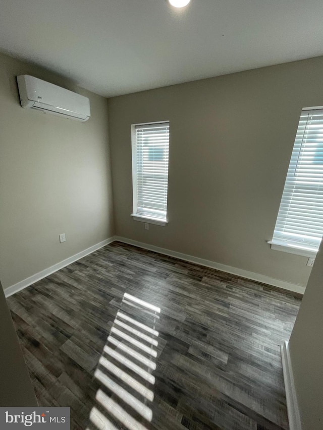 empty room featuring a wall mounted AC, a healthy amount of sunlight, and dark wood-type flooring