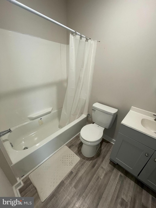 full bathroom with hardwood / wood-style floors, shower / tub combo, vanity, and toilet