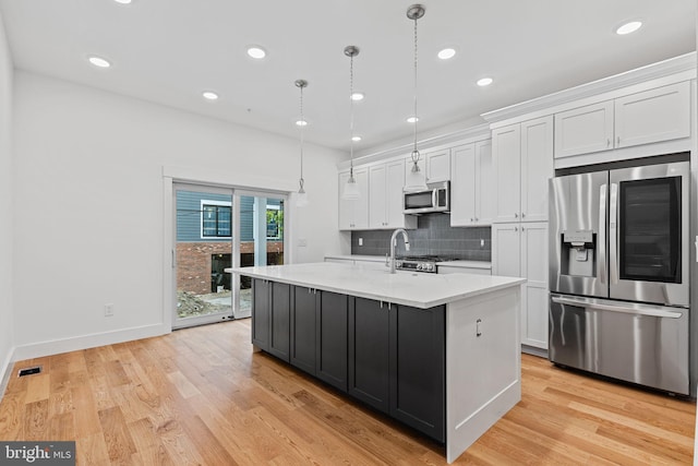 kitchen with white cabinetry, decorative light fixtures, a kitchen island with sink, and stainless steel appliances