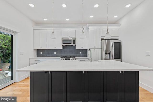 kitchen with a spacious island, stainless steel appliances, white cabinetry, and decorative light fixtures