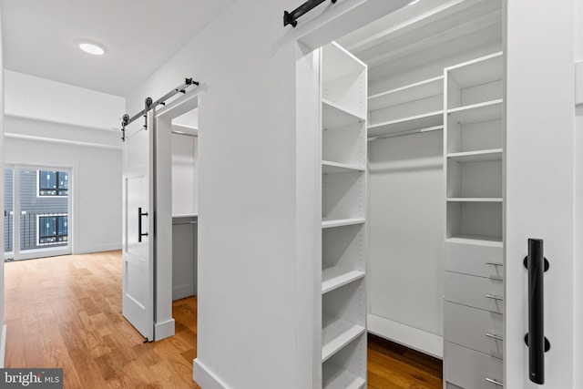 spacious closet with a barn door and light wood-type flooring