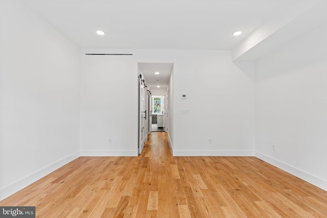 unfurnished room featuring light hardwood / wood-style floors and a barn door