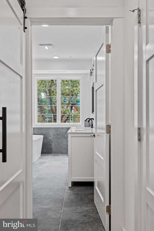 bathroom with a bathing tub, sink, and tile walls