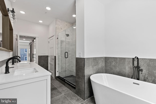 bathroom with tile walls, vanity, plus walk in shower, and tile patterned flooring