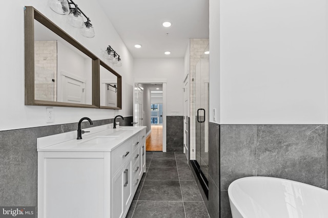 bathroom with vanity, independent shower and bath, tile walls, and tile patterned flooring