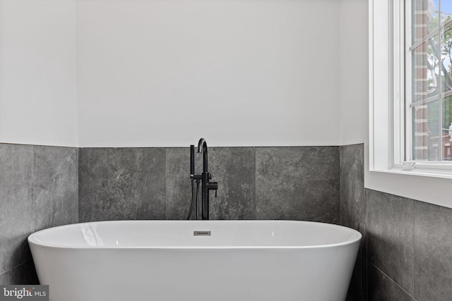 bathroom with tile walls, sink, and a bath