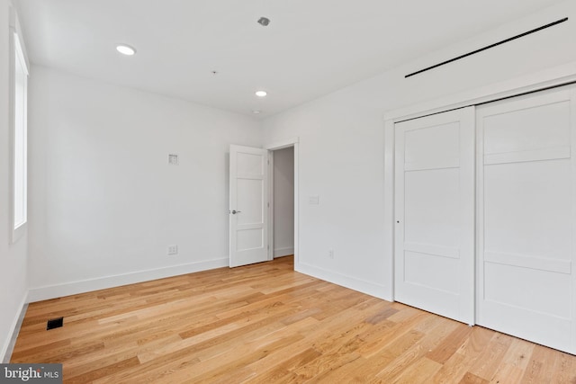 unfurnished bedroom with a closet and light wood-type flooring